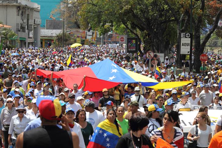 Thousands of people line the streets in Venezuela, holding the red, yellow and blue flag of their country during a protest